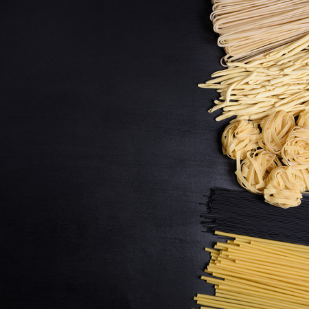 Variety of Italian dry pasta on a black background. Top view, copy space.の写真素材