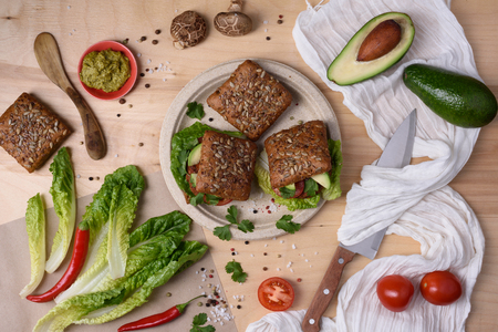 Homemade avocado veggie burgers on wooden board with ingredients, top view.の写真素材