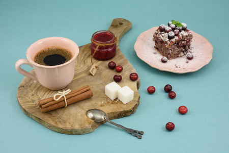 Coffee and chocolate cake with cranberry jam and cinnamon on wooden board, over turquoise background.の写真素材