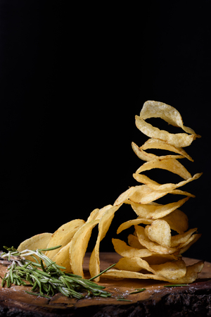 Stack of potato chips with herbs, tasty snack on wood, closeup.の写真素材