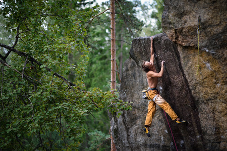 Outdoor sport. Rock climber dangles in midair as he struggles to climb a challenging cliff.の写真素材