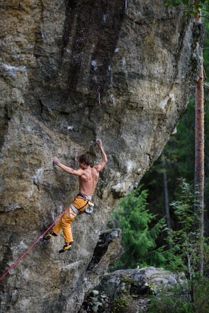 Outdoor sport. Rock climber struggles to climb a challenging cliff.の写真素材