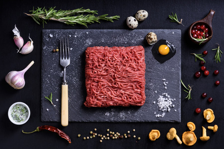 Raw fresh lamb meat with condiments, cooking ingredients on black background. Top view, flat lay.の写真素材