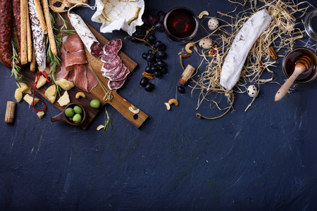 Appetizer, italian antipasto, Ham, Olives, Cheese, Grissini bread sticks,  Sausage on dark blue background copy space. Top view, copy space.の写真素材