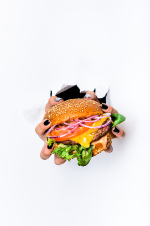 Hands holding cheeseburger with beef cutlet. Close up, Fast food. White background.の写真素材