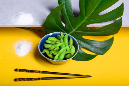 Edamame steamed beans, soybeans sprinkled with salt in the pod. Japanese snack, asian cuisine. Grey and yellow background.の写真素材