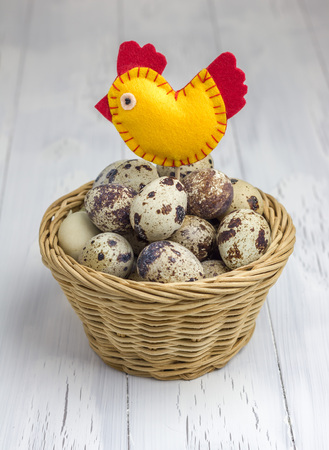 Many quail eggs in the basket, decorated with a handmade bird