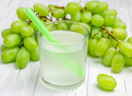 Glass of white grapes juice and grapes on backgroundの写真素材