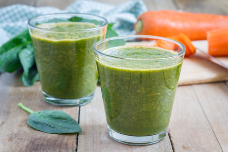 Healthy green spinach carrot smoothie in a glassの写真素材