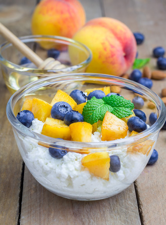 Fresh cottage cheese with peach, blueberry, almonds and honey. Concept of healthy eating for breakfast.の写真素材
