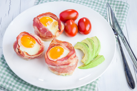 Baked eggs with avocado in bacon cups for breakfastの写真素材