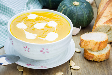 Pumpkin soup with sour cream on a wooden tableの写真素材