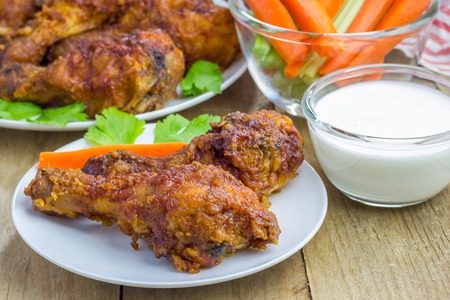Roasted chicken served with celery and carrot sticks, blue cheese dressing and hot sauceの写真素材