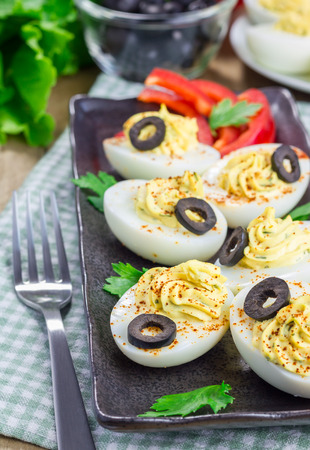 Spicy deviled eggs garnished with olivesの写真素材