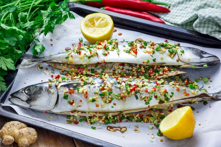 Asian style mackerel with ginger, red chilli, coriander and spring onion on a baking tray, ready to bakeの写真素材
