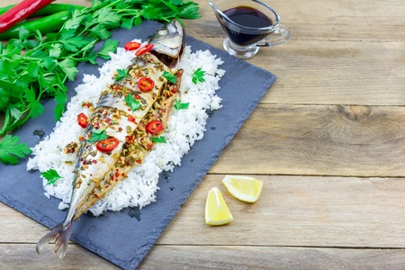 Asian style mackerel baked with ginger, red chili, coriander and spring onion on a bed of fluffy riceの写真素材