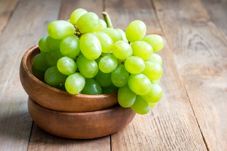 Bunch of green ripe grapes in a wooden bowlの写真素材