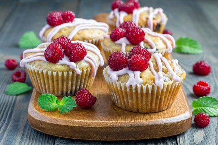 Banana bread muffins with raspberries, cherries and white chocolate on wooden boardの写真素材