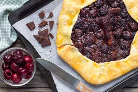 Cottage cheese dough galette with cherries and chocolate on baking tray, top viewの写真素材