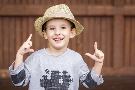 Portrait of four years old boy in hat, playing cowboy, over brown wooden backgroundの写真素材