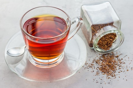 Cup of healthy herbal rooibos red tea in glass cup and dry tea on backgroundの写真素材