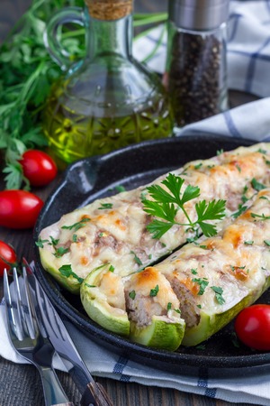 Zucchini boats stuffed with ground meet and topped with cheese on a cast iron pan, verticalの写真素材