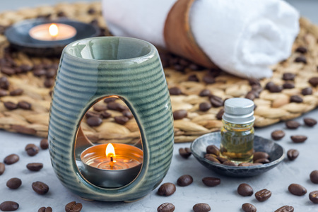 Aroma lamp with coffee essential oil on woven mat, spa background, horizontal