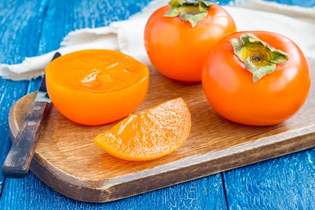 Cut persimmon fruits on wooden board and table, ready to eat, horizontalの写真素材