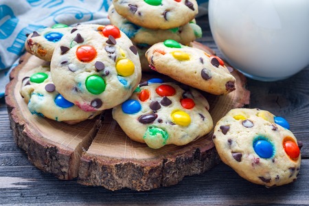 Shortbread cookies with multi-colored candy and chocolate chips on wooden board, horizontal