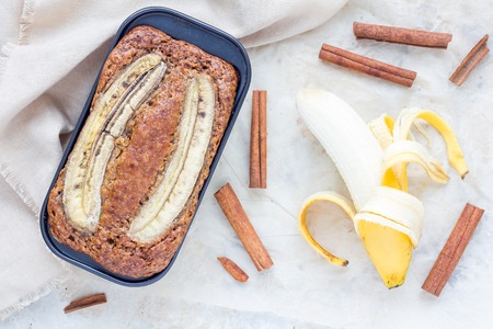 Freshly baked homemade banana cinnamon muffins with slice of banana on top in baking dish, top viewの写真素材