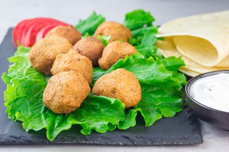 Chickpea falafel balls on slate board with vegetables and sauce, horizontalの写真素材