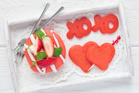 Stack of red velvet pancakes with xo sign (hugs and kisses) and heart on wooden tray, horizontal, top viewの写真素材