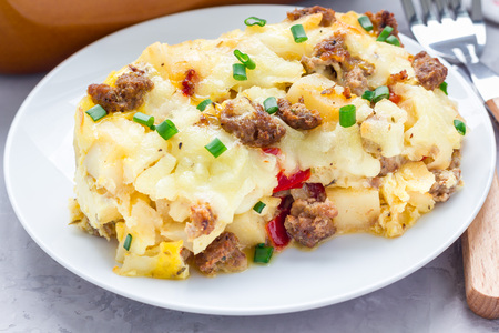 Egg casserole with potatoes, sausage and pepper, on white plate, horizontalの写真素材