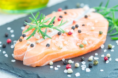 Fresh raw salmon steak with seasonings on stone board, horizontalの写真素材
