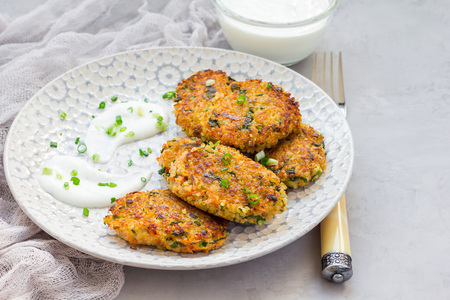 Vegetarian quinoa, carrot, coriander and green onion fritters served with yogurt on plate,...