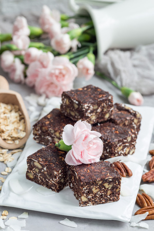 Paleo chocolate energy bars with rolled oats, pecan nuts, dates, chia seeds and coconut flakes, verticalの写真素材