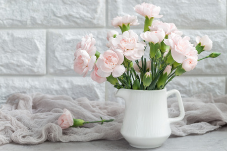 Small tender pink carnation flowers in vase on gray concrete with copy space, mother's day greeting card background, horizontalの写真素材
