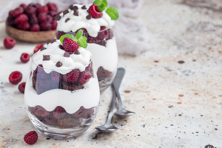 Trifle dessert with brownie, cream cheese frosting and raspberry in a glass, copy spaceの写真素材