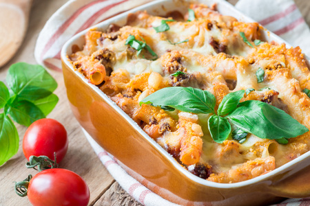 Ziti bolognese in baking dish, pasta casserole with minced meat, tomato sauce and cheese, horizontal