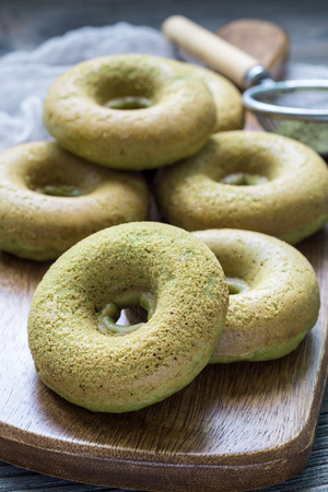 Freshly baked matcha banana donuts on wooden board, verticalの写真素材