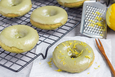 Freshly baked matcha banana donuts with matcha citrus glaze, on cooling rack and table, horizontalの写真素材