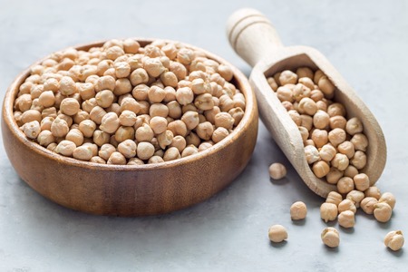 Uncooked dry chickpeas in wooden bowl and in the scoop, horizontalの写真素材