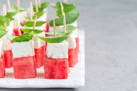 Watermelon salad or caprese with watermelon, feta and basil on a white board, horizontal, copy spaceの写真素材