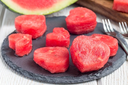 Slices of fresh seedless watermelon cut into heart shape on a slate board, horizontalの写真素材