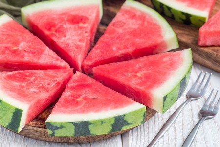 Slices of fresh seedless watermelon cut into triangle shape on a wooden plate, horizontalの写真素材