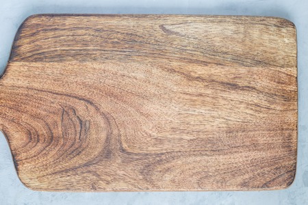 Empty wooden cutting board on gray concrete background, copy space, top view, horizontal