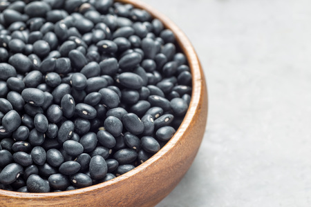 Black beans in a wooden bowl on gray concrete background, horizontal, copy spaceの写真素材