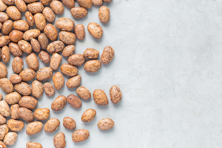 Uncooked dry pinto beans on a gray concrete background, top view, copy space, horizontal