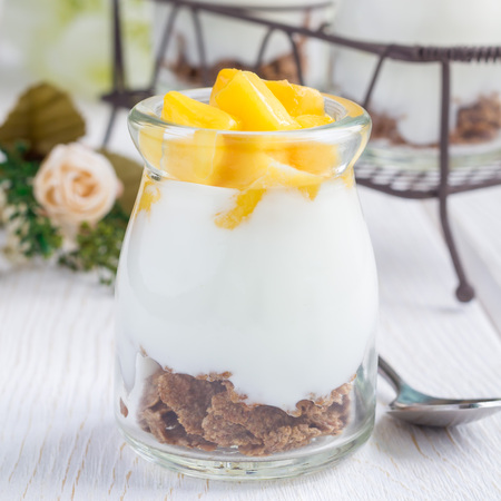 Breakfast dessert with bran flakes, plain yogurt and mango, square formatの写真素材