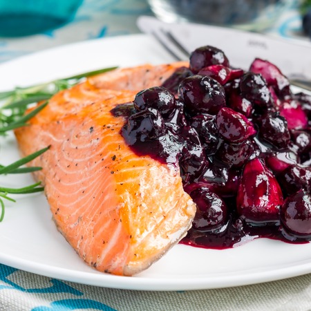 Baked salmon fillet with blueberry and rosmarin sauce on a white plate, square formatの写真素材